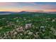 Aerial view of home surrounded by lush trees with mountain views at sunset at 8045 Eagle Rd, Larkspur, CO 80118