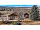 Two-story house in a rural setting featuring a combination of stone and tan siding, and a lush green lawn at 3441 Medallion Rd, Castle Rock, CO 80104