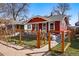 Charming red house featuring a fenced front yard with new plantings, sidewalk, and inviting curb appeal at 4452 Zenobia St, Denver, CO 80212