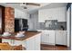 Bright kitchen featuring stainless steel appliances, white cabinets, and a brick accent wall at 4452 Zenobia St, Denver, CO 80212