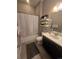 Neutral bathroom with a shower/tub combo, white shower curtain, floating shelves, and a dark vanity at 7790 S Queensburg Way, Aurora, CO 80016