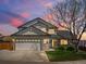 Charming two-story home with a brick facade, a well-manicured lawn, and a spacious two car garage at dusk at 13972 Hudson Way, Thornton, CO 80602