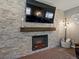 Modern fireplace with a stone surround, wooden mantel, and a large flat-screen TV above at 13972 Hudson Way, Thornton, CO 80602
