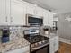 Contemporary kitchen equipped with stainless steel appliances, granite countertops, and white cabinetry at 13972 Hudson Way, Thornton, CO 80602