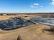 An aerial view of a community park with frozen ponds, walking paths, and a park building on a clear, sunny day at 11423 Steele St, Thornton, CO 80233