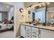 Bathroom with a double vanity, granite countertops, modern fixtures, and a view into the main bedroom at 1798 Summerglow Ln, Monument, CO 80132
