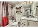 Clean bathroom with a shower-tub combination, wooden shelving, and a well-lit mirror at 1798 Summerglow Ln, Monument, CO 80132