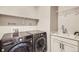 Functional laundry room featuring modern washer and dryer set, utility sink, and ample storage shelving at 1798 Summerglow Ln, Monument, CO 80132