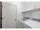 Functional laundry room with white appliances, shelving, and a convenient door at 9811 Crystallo Ct, Parker, CO 80134