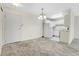 Living area featuring a kitchen with white cabinets, appliances, neutral carpet, and a hanging light fixture at 7801 W 35Th Ave # 409, Wheat Ridge, CO 80033