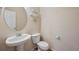 Small powder room featuring white fixtures, round mirror, and a decorative wall shelf at 12728 Jasmine St # E, Thornton, CO 80602
