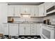 Well-lit kitchen with white cabinets, countertops, stainless steel appliances, and black and white flooring at 1223 Race St # 101, Denver, CO 80206