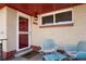Inviting front porch with seating area and a stylish red door with a 'Welcome' mat at 3559 Hudson St, Denver, CO 80207