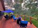 Outdoor deck featuring wood floors and railing, blue patio furniture, and surrounding trees at 20033 Silver Ranch Rd, Conifer, CO 80433