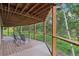 Picture-perfect covered deck with wooden floors, glass railings and green outdoor scenery at 20033 Silver Ranch Rd, Conifer, CO 80433