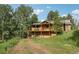 Charming two-story cabin with a welcoming front porch and balcony nestled among lush greenery and mature trees in a serene setting at 20033 Silver Ranch Rd, Conifer, CO 80433
