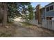 Landscaped backyard featuring a walking path, tall trees, and a glimpse of nearby garages at 2748 S Kenton Ct, Aurora, CO 80014