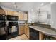Kitchen with light wood cabinets, granite countertops, black appliances, and breakfast bar at 6001 S Yosemite St # H204, Greenwood Village, CO 80111