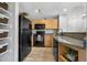 Kitchen with light wood cabinets, black appliances, granite counters, and open display shelving at 6001 S Yosemite St # H204, Greenwood Village, CO 80111