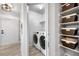 Hall laundry closet with washer, dryer, and overhead shelving storage for baskets at 6001 S Yosemite St # H204, Greenwood Village, CO 80111