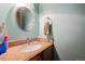 Cozy powder room featuring a granite countertop vanity and a round, decorative mirror at 2567 Rainbow Dr # 80, Denver, CO 80229