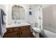 Bathroom with wood vanity, white sink and toilet, and white tub with a seashell pattern shower curtain at 5995 W Hampden Ave # 20B, Denver, CO 80227
