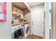 Efficient laundry room with modern washer and dryer, storage cabinets, and door to the exterior at 13871 Ivy St, Thornton, CO 80602