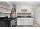 Efficient kitchen with white cabinets, dark countertops, and appliances, enhanced by gray flooring at 741 Quitman St, Denver, CO 80204