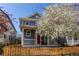 Charming two-story home with a red door, inviting front porch, well-manicured lawn, and beautiful flowering tree at 3353 Wabash St, Denver, CO 80238