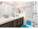Bright bathroom featuring double sinks, dark vanity, and walk-in shower at 2795 Signal Creek Dr, Thornton, CO 80241