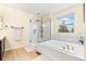 Bright bathroom featuring a soaking tub, glass shower, and natural light from a bright window at 2795 Signal Creek Dr, Thornton, CO 80241