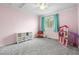 Spacious bedroom with pink walls, toy storage, and a large window with curtains at 2795 Signal Creek Dr, Thornton, CO 80241