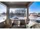 A covered balcony with wicker furniture, overlooking a snow-covered landscape at 1312 Independence St # 3, Lakewood, CO 80215