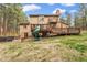 Large backyard showcasing a deck with slide, patio with hot tub, and grassy lawn at 17540 Caribou Dr, Monument, CO 80132