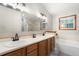 Bright bathroom featuring a double vanity, large mirror, tub and glass shower at 17540 Caribou Dr, Monument, CO 80132
