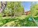 Lush backyard featuring mature trees, a wooden deck, a grassy lawn, and outdoor seating, perfect for relaxing outdoors at 879 S Cole Dr, Lakewood, CO 80228