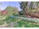 Charming backyard featuring lush greenery, a white picket fence, and mature trees, creating a serene outdoor space at 879 S Cole Dr, Lakewood, CO 80228