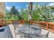 Outdoor deck with table, chairs and an umbrella, overlooking the trees and sky at 879 S Cole Dr, Lakewood, CO 80228