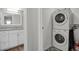 Convenient laundry area with stacked washer and dryer, adjacent to a bathroom with modern vanity and decorative flooring at 3872 S Fraser St # O03, Aurora, CO 80014