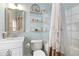 Well-lit bathroom featuring a vanity sink, tiled shower with decorative curtains, and stylish shelving at 858 S Emerson St, Denver, CO 80209