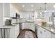 Updated kitchen featuring white cabinets, a breakfast bar, modern appliances, granite countertops, and tile flooring at 858 S Emerson St, Denver, CO 80209