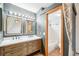 Bathroom with dual sinks, framed mirrors, modern lighting, and a view of a tiled shower/tub combo at 12690 W Brandt Dr, Littleton, CO 80127