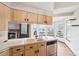 Well-lit kitchen with a double basin sink, light wood cabinets, and stainless steel dishwasher at 12690 W Brandt Dr, Littleton, CO 80127