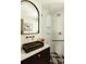 Elegant bathroom featuring a modern sink, an arched mirror, and glass-enclosed shower with gold shower head at 2060 Kline St, Lakewood, CO 80215