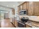 Updated kitchen with stainless steel appliances, wood cabinets, stone countertops, and hardwood floors at 12993 E 108Th Ave, Commerce City, CO 80022