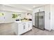 Bright kitchen features white cabinets, stainless steel refrigerator, and a quartz island at 2767 W Iliff Ave # 1, Denver, CO 80219