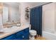 Bathroom with blue vanity, white countertops, decorative mirror, and shower with blue curtain at 32 Powder Horn Pl, Longmont, CO 80504