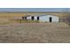 Two white metal barns sit on a property with horse stalls and mountain views in the background at 74500 E 136Th Ave, Byers, CO 80103
