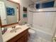 Bathroom featuring white tile, wood-framed mirror, and a shower-tub with a blue accent line at 6272 S Garfield Dr, Centennial, CO 80121