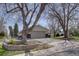 View of the property showcasing a paved driveway leading to a garage, complemented by a brick-accented base and mature trees at 6272 S Garfield Dr, Centennial, CO 80121